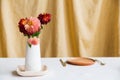 Autumn table decor. A bouquet of red dahlia flowers stands in a vase in the middle of the table against a yellow fabric Royalty Free Stock Photo