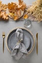 Autumn table setting with dry yellow oak leaves, fall decoration and golden cutlery on grey. Thankisgiving day Royalty Free Stock Photo