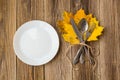 Thanksgiving dinner plate with fork, knife and autumn leaves on rustic wooden table background. Top view, copy space Royalty Free Stock Photo