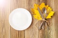 Thanksgiving dinner plate with fork, knife and autumn leaves on rustic wooden table background. Top view, copy space Royalty Free Stock Photo