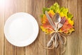 Thanksgiving dinner plate with fork, knife and autumn leaves on rustic wooden table background. Top view, copy space Royalty Free Stock Photo