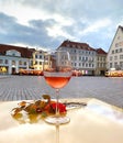 Glass of wine red rowan branch and on table at street cafe in town hall square in rainy Tallinn old town medieval city houses