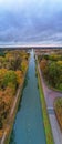 Autumn Tapestry: Aerial View of River or Canal Flowing Through Colorful Woods Under a Dramatic Cloudy Sky
