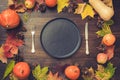 Autumn and Thanksgiving day table setting with fallen leaves, pumpkins, spices, empty black platter and vintage cutlery on brown w Royalty Free Stock Photo