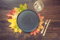 Autumn and Thanksgiving day table setting with fallen leaves, spices, black dish and silverware on wooden table. Top view Royalty Free Stock Photo