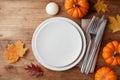 Autumn Thanksgiving table setting for dinner with plate, knife, fork decorated pumpkins and maple leaves. Top view Royalty Free Stock Photo