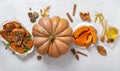 Autumn theme. A whole large pumpkin, pumpkin dishes, yellow leaves, honey on a light concrete background