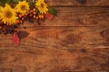 Autumn theme. Wooden background with sunflower flowers, berries and leaves in the corner