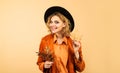 Autumn time. Smiling young woman in black hat with autumn leaves. Leaf fall. Fashion girl in orange shirt and jacket