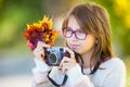Autumn time. The teenage attractive cute young girl with autumn bouquet and retro camera. Young girl photographer autumn season Royalty Free Stock Photo