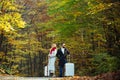 Autumn tourist couple with suitcase. Beautiful fall day. Pretty woman and handsome man walking in the Park and enjoying