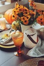 Autumn traditional seasonal table setting at home with pumpkins, candles and flowers Royalty Free Stock Photo