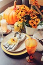 Autumn traditional seasonal table setting at home with pumpkins, candles and flowers Royalty Free Stock Photo