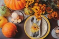 Autumn traditional seasonal table setting at home with pumpkins, candles and flowers