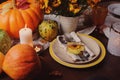 Autumn traditional seasonal table setting at home with pumpkins, candles and flowers