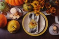 Autumn traditional seasonal table setting at home with pumpkins, candles and flowers Royalty Free Stock Photo