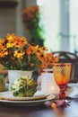Autumn traditional table setting for Thanksgiving or Halloween, with candles, flowers and pumpkins.
