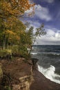 Autumn trees along scenic Superior lake shore with waves hitting rocks. Royalty Free Stock Photo