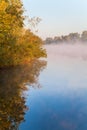 Autumn forest with bright foliage reflected in blue water of the river Dnipro, fog over the river, sunny morning. Ukraine Royalty Free Stock Photo