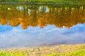 Autumn trees with golden leaves reflected in the clear water of the lake