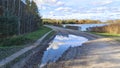 In autumn, the trees have yellow leaves and after the rain, a puddle was formed on a country road in which the blue sky with cloud Royalty Free Stock Photo