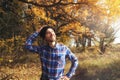 Autumn vibes. Happy cheerful bearded man in knitted hat enjoying sunny day in fall forest Royalty Free Stock Photo