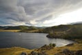 Autumn view of bay of Lake Baikal with hills and mountains. Blue water, yellow and green trees. Cloudy sky. Siberia Royalty Free Stock Photo