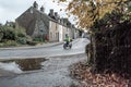 Autumn view of a commuter seen riding his Scooter during wet weather.