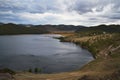 Autumn view of round bay of Lake Baikal with hills and mountains covered with green trees . Shore of Maloe More.