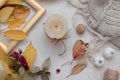 Autumn flat lay view with fallen leaves, dry rose, candles and knitted sweater