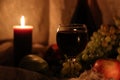 Autumn still life. Thanksgiving post card. Glass full of red wine with candle light reflection and fruits on background Royalty Free Stock Photo