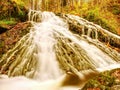 Autumn waterfall in basalt rock. Shinning streams and many colorful leaves on banks Royalty Free Stock Photo