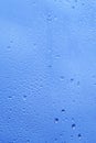 Autumn window with the texture of water drops against a cloudy blue sky. Glass background with drops of rain Royalty Free Stock Photo