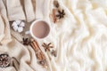 Autumn or winter composition. Coffee cup, cinnamon sticks, anise stars, beige sweater on cream color knitted blanket background.