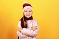 Autumn and winter concept. Portrait of a cute little girl in a jacket, scarf and hat on a yellow background Royalty Free Stock Photo