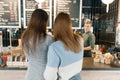 Autumn winter portrait of two young women standing with their backs near the bar counter in coffee shop, girls talking to a Royalty Free Stock Photo