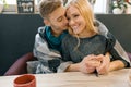 Autumn winter portrait of young embracing couple. Young man and woman in cafe under warm woolen blanket drinking coffee tea, happy Royalty Free Stock Photo