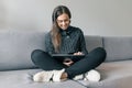 Autumn winter portrait of young girl in warm knitted sweater at home on sofa with digital tablet Royalty Free Stock Photo