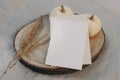 Autumn, winter stationery still life. Closeup of lank greeting card, invitation mockup on cut wooden round board. Dry