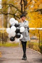 Autumn woman in autumn park with balloons. Fashion girl in gray coat