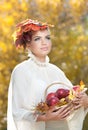 Autumn Woman. Beautiful creative makeup and hair style in outdoor shoot . Girl with leaves in hair holding a basket with apples Royalty Free Stock Photo