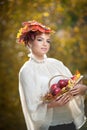 Autumn Woman. Beautiful creative makeup and hair style in outdoor shoot . Girl with leaves in hair holding a basket with apples Royalty Free Stock Photo