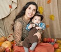 Autumn woman with little boy on yellow fall leaves, apples, pumpkin and decoration on textile, happy family and country concept Royalty Free Stock Photo