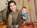 Autumn woman with little boy on yellow fall leaves, apples, pumpkin and decoration on textile, happy family and country concept Royalty Free Stock Photo