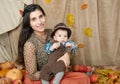 Autumn woman with little boy on yellow fall leaves, apples, pumpkin and decoration on textile, happy family and country concept Royalty Free Stock Photo