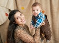 Autumn woman with little boy on yellow fall leaves, apples, pumpkin and decoration on textile, happy family and country concept Royalty Free Stock Photo