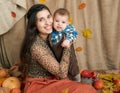 Autumn woman with little boy on yellow fall leaves, apples, pumpkin and decoration on textile, happy family and country concept Royalty Free Stock Photo