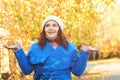 Autumn woman presenting something on empty palms on nature background. Autumn season. Woman in blue coat and knitted hat enjoying