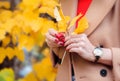 Autumn. Woman with yellow maple leaves and red berries in her hands. A girl in a coat walks in the park outdoors.