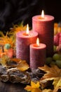 Autumnal arrangement with three lit candles and fall leaves Royalty Free Stock Photo